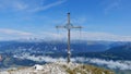 Mountain peak cross with cloudy blue sky in the background