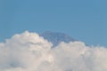Mountain peak emerging above thick white clouds under a clear blue sky Royalty Free Stock Photo