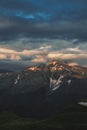 Mountain peak sunset landscape with gloomy dramatic mainly cloudy sky and orange and red sun beams Royalty Free Stock Photo