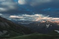 Mountain peak sunset landscape with gloomy dramatic mainly cloudy sky and orange and red sun beams Royalty Free Stock Photo