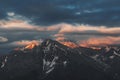 Mountain peak sunset landscape with gloomy dramatic mainly cloudy sky and orange and red sun beams Royalty Free Stock Photo