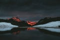 Mountain peak sunset in red with black colours and lake reflection Royalty Free Stock Photo