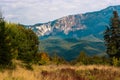 Mountain peaks and fir trees catching warm sunbeams. Nice meadow in the foreground Royalty Free Stock Photo