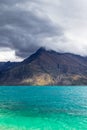 Mountain peaks up to clouds over turquoise water. Rainy day at Lake Wakatipu, New Zealand Royalty Free Stock Photo