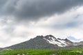 Mountain range with glaciers on slope under gloomy sky. Rainy gray clouds over snowy cliffs. Planning climb to top Royalty Free Stock Photo