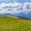 Mountain range with green meadows, flowers and blue sky with big white clouds. Relaxing and peaceful nature scene. Spanish