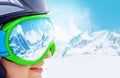 Portrait of young woman at the ski resort on the background of mountains and blue sky.A mountain range reflected in the ski mask Royalty Free Stock Photo