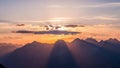 Mountain range silhouetted against a vibrant sunset with dramatic sun rays and soft clouds Royalty Free Stock Photo