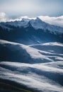 a mountain range with snow on the top and a few clouds in the sky above it and below it Royalty Free Stock Photo