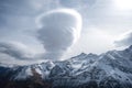 Mountain range, steep snow-covered slopes and large bizarre cloud