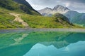 Mountain reflection in the calm turquoise water of an artificial reservoir high up in the Tyrolean mountains, Austria.