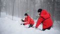 Mountain rescue service on operation outdoors in winter in forest, digging snow with shovels. Royalty Free Stock Photo