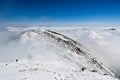 Mountain ridge and sea of clouds; the tops of Mount San Gorgonio and Mount San Jacinto in the background; hiker coming up a steep