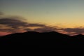 Mountain ridge silhouette landscape background of moody dramatic weather time with soft color orange sunset lighting Royalty Free Stock Photo