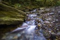 Mountain river of crystalline water in a lush forest on a rocky bed, long exposure