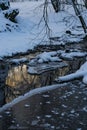 A mountain river flows slowly in winter in a forest with snow and ice Royalty Free Stock Photo