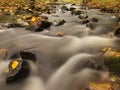 Mountain river with low level of water, gravel with first colorful leaves. Mossy rocks and boulders on river bank. Royalty Free Stock Photo