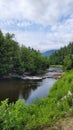 Mountain river rapids in rocky waters creek with mountains clouds and Evergreen forests in Adirondack Park New York