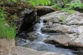 Mountain river - a small waterfall on a river with crystal clear water that flows among gray stones in a green forest on Royalty Free Stock Photo