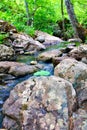 Mountain river - a small waterfall on a river with crystal clear water that flows among gray stones in a green forest on Royalty Free Stock Photo