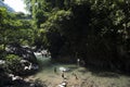 river with unrecognizable children playing in clean water, rainforest jungle with leafy trees in the Amazon Tingo Maria