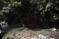 river with unrecognizable children playing in clean water, rainforest jungle with leafy trees in the Amazon Tingo Maria