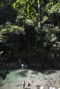 river with unrecognizable children playing in clean water, rainforest jungle with leafy trees in the Amazon Tingo Maria