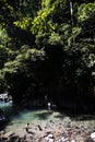 river with unrecognizable children playing in clean water, rainforest jungle with leafy trees in the Amazon Tingo Maria