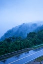 Mountain road in foggy dusk, asphalt road through the mountain top of Phnom Bokor Mountain in rainy day, Preah Monivong Bokor Royalty Free Stock Photo