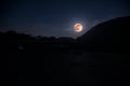 Mountain Road through the forest on a full moon night. Scenic night landscape of dark blue sky with moon. Azerbaijan