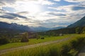 Mountain road leading to the village in the Austrian Alps. Beautiful alpine landscape with green meadows Royalty Free Stock Photo