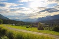 Mountain road leading to the village in the Austrian Alps. Beautiful alpine landscape with green meadows Royalty Free Stock Photo