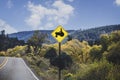 Mountain road  with ridge and fall trees in background and caution sign displaying man on tractor.j Royalty Free Stock Photo