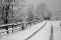 Mountain road in the snow. Traces of car tires. Trees in the snow. A wooden fence in the snow along the road. Black and white Royalty Free Stock Photo