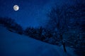 Mountain Road through the snowy forest on a full moon night. Scenic night winter landscape of dark blue sky with moon and stars Royalty Free Stock Photo