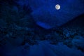 Mountain Road through the snowy forest on a full moon night. Scenic night winter landscape of dark blue sky with moon and stars Royalty Free Stock Photo