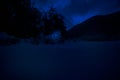 Mountain Road through the snowy forest on a full moon night. Scenic night winter landscape of dark blue sky with moon and stars Royalty Free Stock Photo