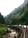 Mountain road, stream, a row of cars parked on the road