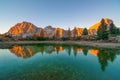 Mountain rocks and autumn trees reflected in water of Limides Lake at sunset, Dolomite Alps, Italy