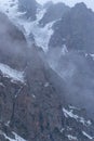 Mountain rocks in the fog and snow on the slopes