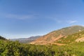 Mountain scenery with lush green trees on gentle slopes and peak on a sunny day Royalty Free Stock Photo