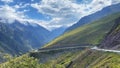 Mountain serpentine roads. Summer landscape. Blue sky and white clouds. Snow-capped mountains, hills, ridges and rocks of Royalty Free Stock Photo