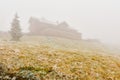Mountain shelter in the fog on a mountain hiking trail, slightly frosted vegetation on a foggy day