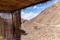 Mountain shelter made of cane and palm tree branches and leafs with mountain view in the background.