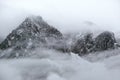 Mountain silhouette fragments through fog and clouds