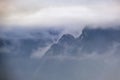 Mountain silhouette fragments through fog and clouds