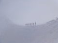 Mountain skiers go together on mountain ridge in snow storm and danger of avalanche, mountain peak Aiguille du Midi in France