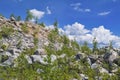 Mountain slope with large stones against a blue summer sky with white cumulus clouds Royalty Free Stock Photo