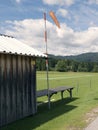 Mountain small airport. Wind sleeve meter. Wooden cottage. Green lawn landing area.