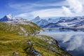 Mountain with snow and green grass with reflection in the lake,